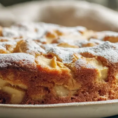 Classic American apple cake dusted with powdered sugar on a ceramic plate