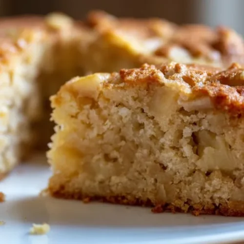 soft apple cake slice with tender crumb and baked apple pieces on white plate