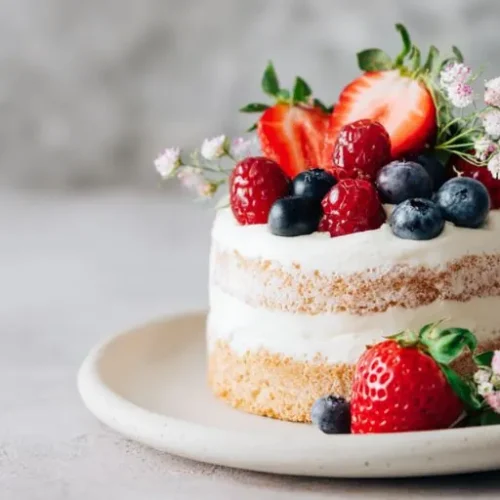 mini naked cake with fresh strawberries blueberries and cream frosting on a plate
