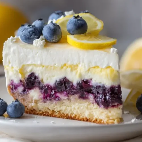 blueberry lemon cheesecake slice with creamy layers topped with fresh blueberries and lemon slices