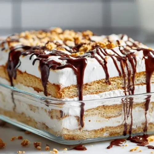 chocolate layered dessert with whipped cream graham layers and chocolate drizzle in glass dish