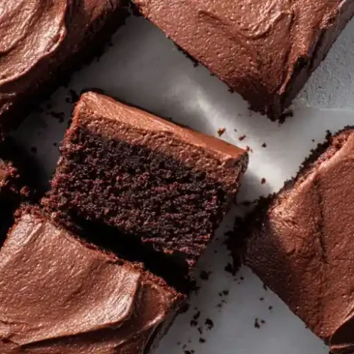 chocolate fudge brownies with rich frosting cut into squares on white surface