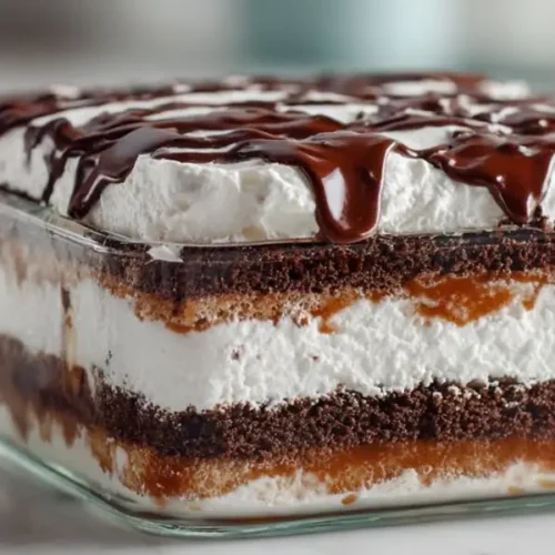 chocolate layered dessert in glass dish with whipped cream layers and chocolate drizzle