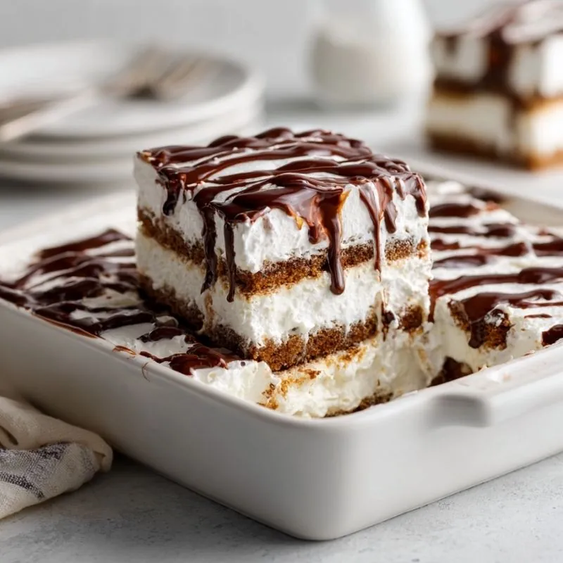 Chocolate Layered Dessert Slice – Creamy No-Bake Treat chocolate layered dessert slice with whipped cream layers and chocolate drizzle in baking dish