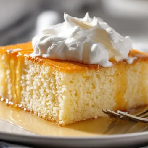 soft vanilla cake topped with whipped cream and caramel sauce on a plate