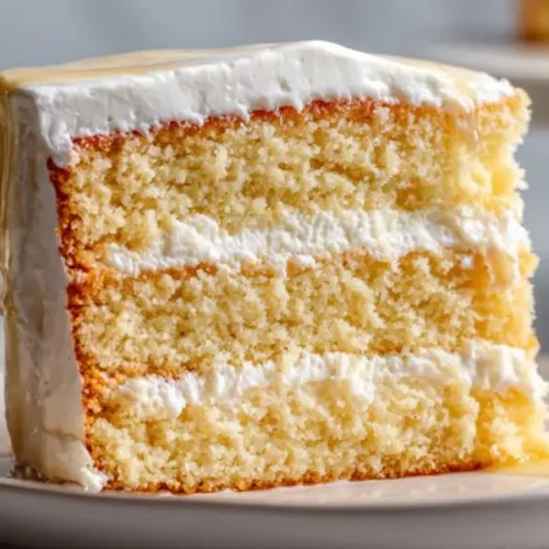 vanilla layer cake with creamy frosting and soft sponge layers on a plate
